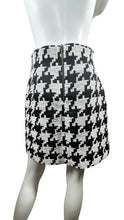 Load image into Gallery viewer, Indulge in the classic and timeless style of the Black and White Houndstooth Skirt. This skirt features a striking houndstooth print, zipper closure, and measured flat waist of 28 inches. With a hip measurement of 37 inches and a flattering length of 1...