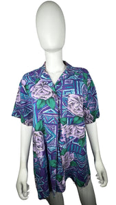 A medium vintage Partners Mervyns short sleeve button up with a purple and blue all-over floral print. The shirt is missing all of the buttons but one and has been well-worn. Measured FlatChest - 36"Sleeve - 9"Length - 28"