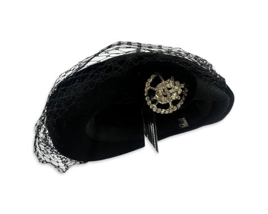 This pillbox hat is a vintage gem, featuring a black velvet design and adorned with a silver and rhinestone brooch. It's Union made and comes in its original box.