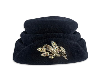 This fab 50's Pillbox Black Hat boasts a luxurious velvet and wool construction, topped off with a dazzling gold and rhinestone brooch. Measuring 8