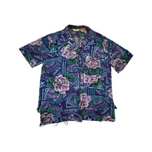 Load image into Gallery viewer, A medium vintage Partners Mervyns short sleeve button up with a purple and blue all-over floral print. The shirt is missing all of the buttons but one and has been well-worn. Measured FlatChest - 36&quot;Sleeve - 9&quot;Length - 28&quot;
