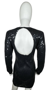 Experience the irresistible glamour of the Vintage Maison Magique Sequin Dress. This stunning black cocktail dress features long sleeves and a mini length, all adorned with sparkling sequins. With a flat chest measurement of 31 inches, sleeve length of...