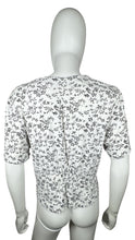 Load image into Gallery viewer, Experience a touch of nostalgia with our Vintage Black and White Floral Crop Top - the perfect blend of old and new. This short sleeve button-up piece features a chest measurement of 34&quot; and a length of 19&quot;, giving you a flattering fit.