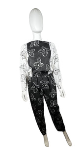 Introducing a one-of-a-kind black and white floral jumpsuit from the 80's, complete with a stretch waist for ultimate comfort. Measurements include: Chest - 39", Sleeve - 24", Waist - 26", Hips - 40", Inseam - 28", Length - 60". Don't miss this rare vi...