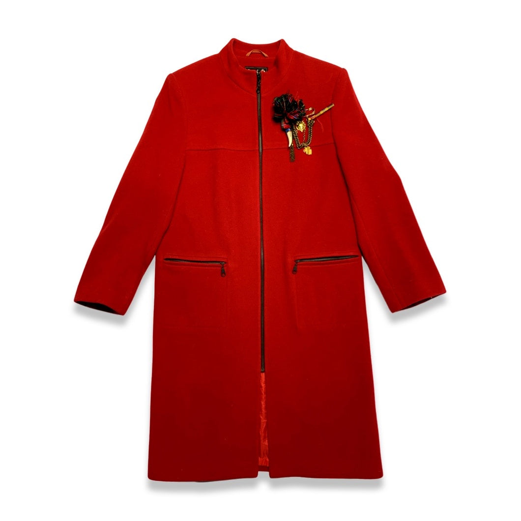 The Vintage KronHaus Coat is a luxurious, bespoke red wool coat. Its unique vintage charm is further enhanced by subtle imperfections near the button zipper area, as shown in the picture. 